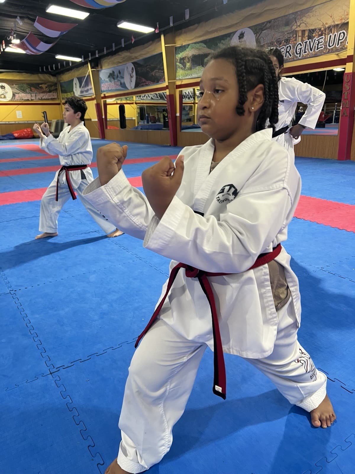 A student with a red-and-black belt in a fighting stance on the training floor